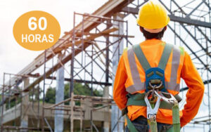 Operario de construcción con casco, chaleco y arnés de seguridad en una obra, ejemplificando la prevención de riesgos laborales y el uso de EPIs.